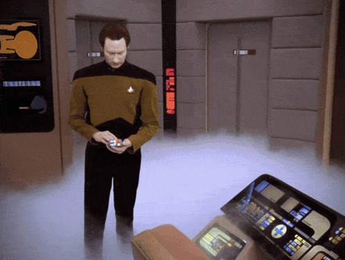A Man In A Star Trek Uniform Is Standing In A Room With A Sign That Says Eo On It GIF