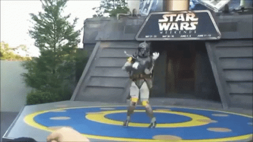 A Man In A Star Wars Costume Is Standing In Front Of A Sign That Says Star Wars Weekends GIF