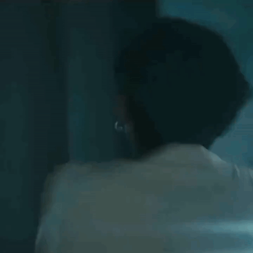 A Man In A Strait Jacket Is Laughing And Smiling In A Dark Room . GIF