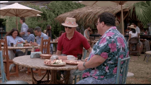 a man in a straw hat sits at a table with a plate of food on it