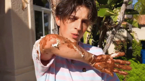A Man In A Striped Shirt Has His Hands Covered In Chocolate GIF