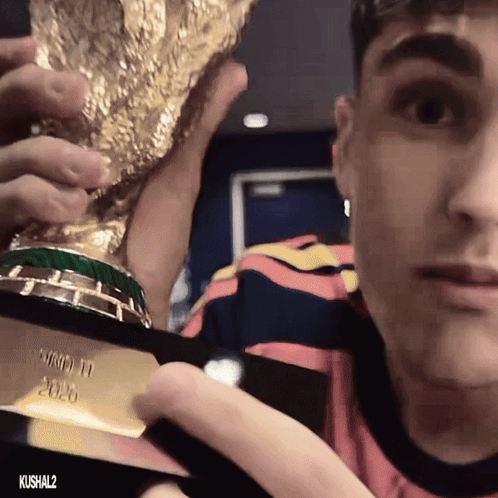 a man in a striped shirt holds a trophy that says world cup 2020