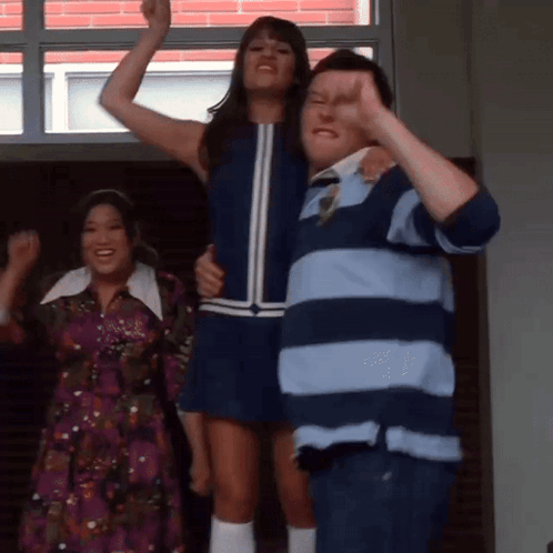 A Man In A Striped Shirt Holds A Woman In A Blue Dress In His Arms GIF