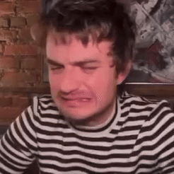 A Man In A Striped Shirt Is Crying And Making A Funny Face . GIF