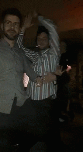 a man in a striped shirt is dancing in a crowd of people