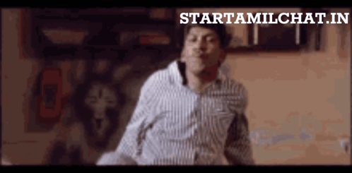 A Man In A Striped Shirt Is Dancing In Front Of A Sign That Says Startamilchat.in GIF