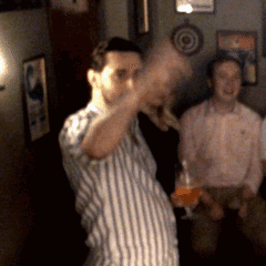 A Man In A Striped Shirt Is Holding A Glass GIF