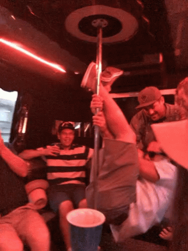 A Man In A Striped Shirt Is Holding A Pole In A Red Room GIF