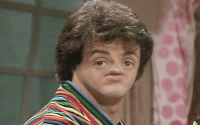 A Man In A Striped Shirt Is Making A Funny Face With His Mouth Open . GIF