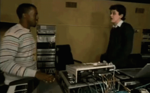 Man In Striped Shirt Shaking Hands With Man In Black Sweater GIF