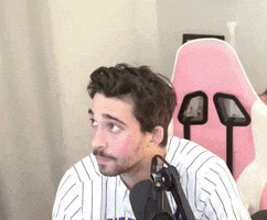 A Man In A Striped Shirt Is Sitting In Front Of A Microphone . GIF