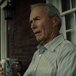 a man in a striped shirt is sitting on a porch holding a cup