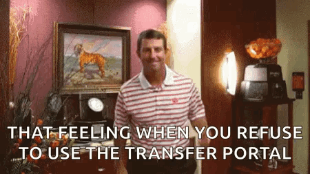 a man in a striped shirt is standing in a room with a painting of a tiger on the wall .