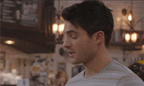 A Man In A Striped Shirt Is Standing In Front Of A Bar . GIF