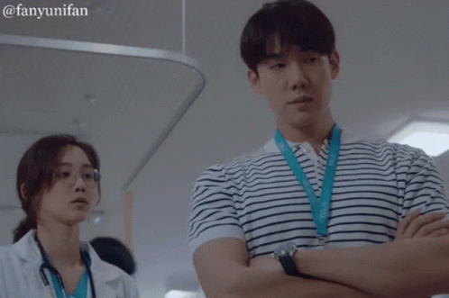 A Man In A Striped Shirt Is Standing Next To A Woman In A White Lab Coat GIF