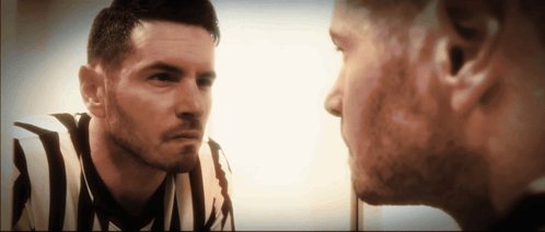 A Man In A Striped Shirt Looks At His Reflection In The Mirror GIF