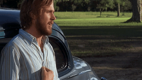 A Man In A Striped Shirt Stands Next To A Car GIF