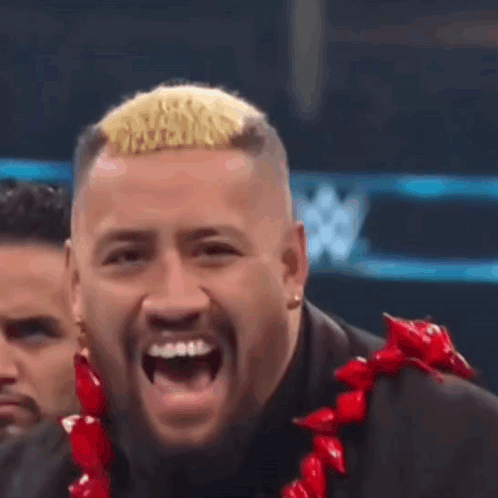 A Man In A Suit And A Red Lei Is Laughing . GIF