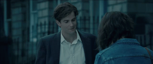 A Man In A Suit And A Woman In A Denim Jacket Are Talking To Each Other GIF