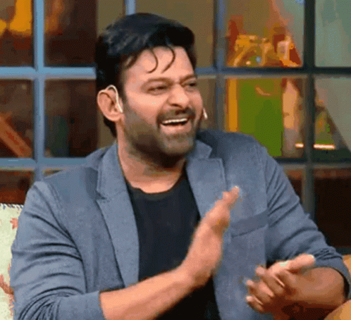 A Man In A Suit And Black Shirt Is Clapping His Hands And Smiling . GIF