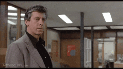 A Man In A Suit And Black Shirt Is Standing In An Office With Movieclips.com On The Bottom Right GIF
