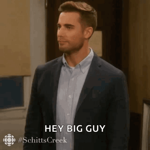 A Man In A Suit And Blue Shirt Is Saying Hey Big Guy . GIF
