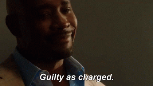 A Man In A Suit And Blue Shirt Is Smiling And Says Guilty As Charged GIF