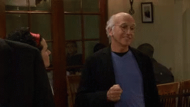 A Man In A Suit And Blue Shirt Is Standing Next To A Woman In A Room And Smiling . GIF