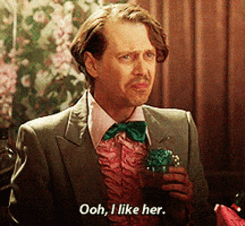 A Man In A Suit And Bow Tie Is Holding A Cupcake And Saying Ooh I Like Her GIF