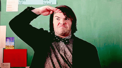 A Man In A Suit And Bow Tie Is Making A Funny Face In Front Of A Chalkboard . GIF