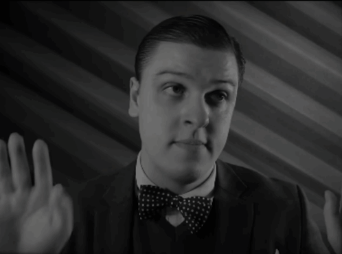 A Man In A Suit And Bow Tie Is Pointing GIF