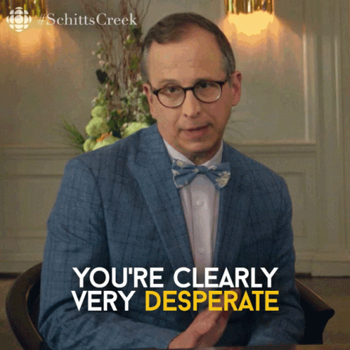 A Man In A Suit And Bow Tie Is Sitting At A Table And Says " You 'Re Clearly Very Desperate " GIF