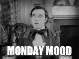 A Man In A Suit And Bow Tie Is Sitting In Front Of A Fireplace With The Words Monday Mood Above Him GIF