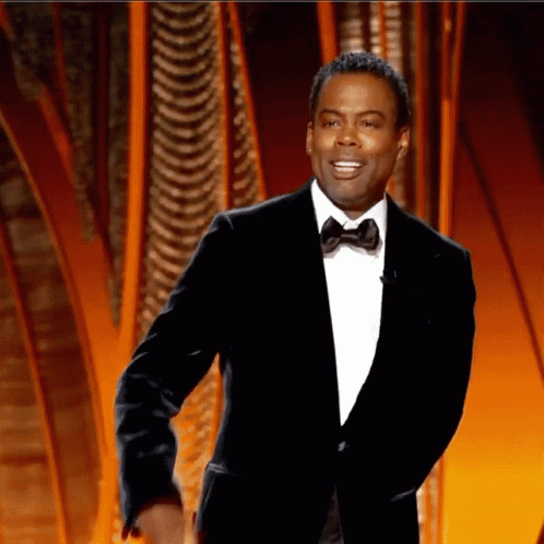 A Man In A Suit And Bow Tie Is Smiling GIF