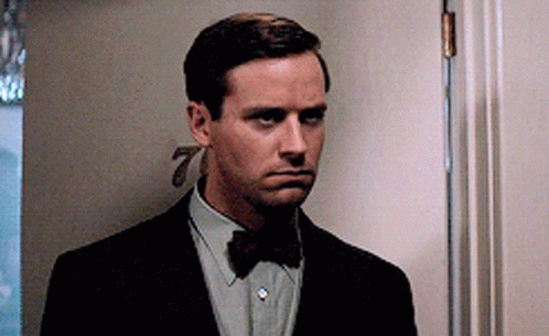 A Man In A Suit And Bow Tie Is Standing In A Doorway GIF