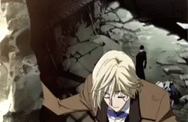 A Man In A Suit And Bow Tie Is Standing In Front Of A Destroyed Building GIF