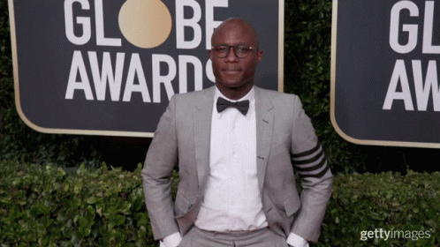 a man in a suit and bow tie is standing in front of a sign that says globe awards