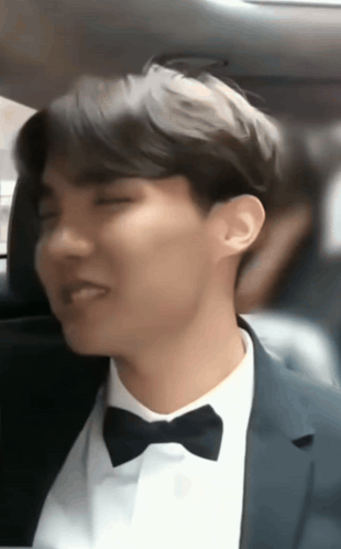 A Man In A Suit And Bow Tie Sitting In A Car GIF
