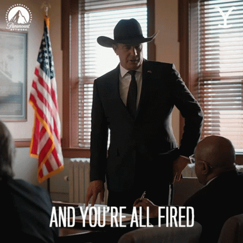 A Man In A Suit And Cowboy Hat Says " And You 'Re All Fired " In Front Of An American Flag GIF