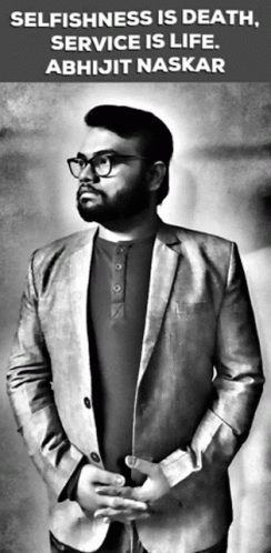 A Man In A Suit And Glasses Is Standing In Front Of A Sign That Says Selfishness Is Death Service Is Life GIF