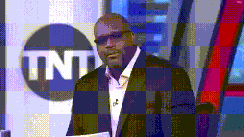 a man in a suit and glasses is standing in front of a tnt logo