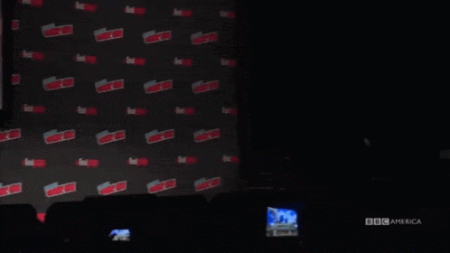 a man in a suit and glasses is standing in front of a wall with the word expo on it .