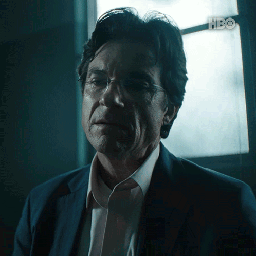 A Man In A Suit And Glasses Looks At The Camera With Hbo Written In The Corner GIF