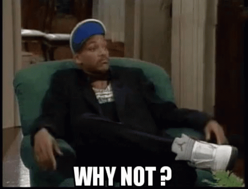A Man In A Suit And Hat Is Sitting In A Chair With His Legs Crossed And Says `` Why Not ? '' . GIF