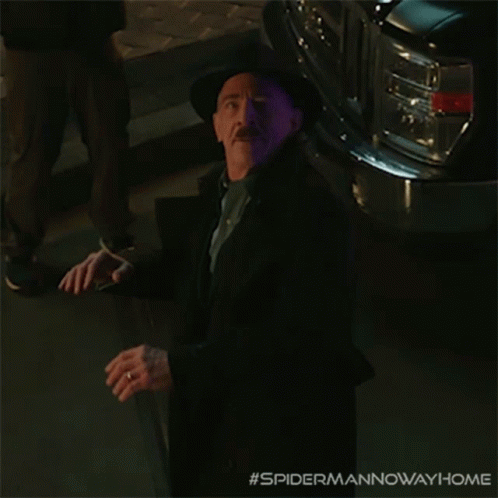 A Man In A Suit And Hat Is Standing In Front Of A Purple Car With The Hashtag #Spidermannowawayhome GIF