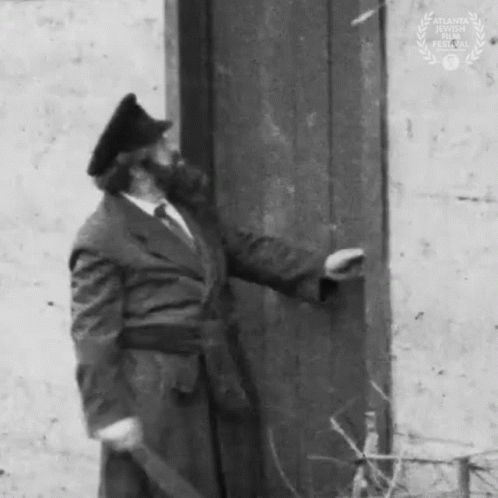 Man In Suit And Hat Standing Next To Door GIF