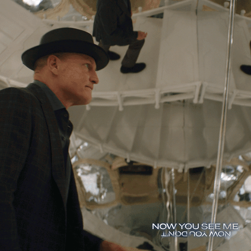 A Man In A Suit And Hat Stands In Front Of A Mirror With The Words Now You See Me GIF