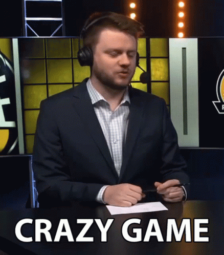 A Man In A Suit And Headphones Sitting At A Table With The Words Crazy Game Written On The Bottom GIF