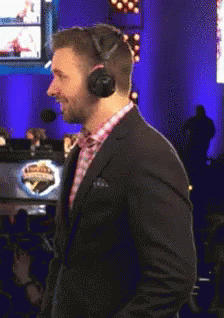 A Man In A Suit And Headphones Stands In Front Of A Sign That Says ' Champions ' On It GIF