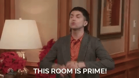 A Man In A Suit And Orange Shirt Is Saying This Room Is Prime . GIF